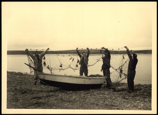 Des hommes tiennent un filet de pèche devant une embarcation