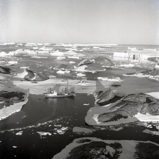 Survol du sud de l'île des Pétrels : îles Buffon, Claude Bernard et Lamarck. Au loin le glacier de l'Astrolabe. Le Thala Dan à l'amarré aux Pétrels.