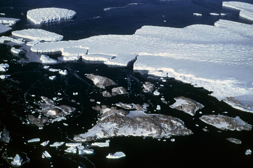 Survol de l'archipel vers l'est. Le front du glacier de l'Astrolabe et les icebergs qui s'en détachent.