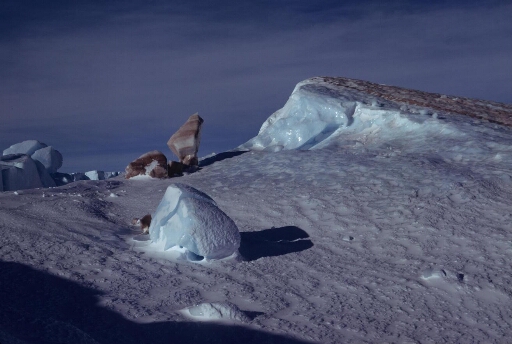 Iceberg retourné : surface érodée et colorée au contact du fond marin. Un bloc coloré en équilibre.
