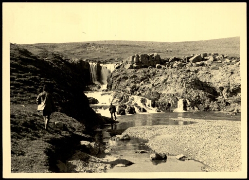 Des hommes devant une cascade.