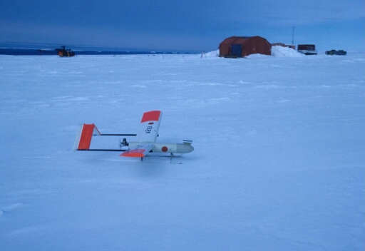Sur le continent, à D10 : sondage météorologique expérimental utilisant ce drone SAM posé sur le névé, moteur tournant prêt à décoller.