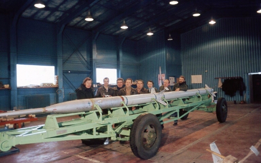 Dans le hangar de montage des fusées, toute l'équipe Fusov pose devant la fusée, sauf Nicolaï.