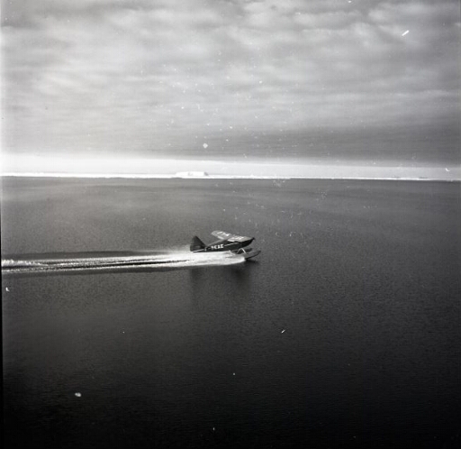 Sur une mer d'huile l'hydravion prend son envol. Le ciel est couvert mais le temps est calme.