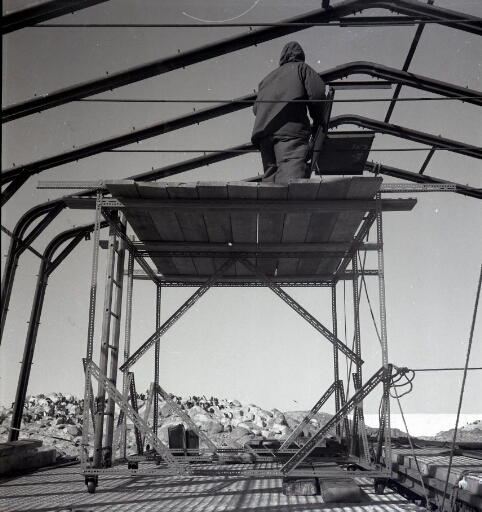 Un homme sur le chantier de construction de l'atelier, type "Fillod": pose des fermes.