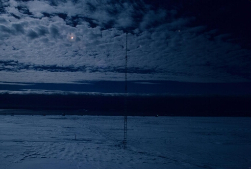 Programme IAGO pour l'étude des vents catabatiques. Sur le continent, à D 10, le pylône aérologique installé. Photo prise au clair de Lune dans un ciel moutonneux.