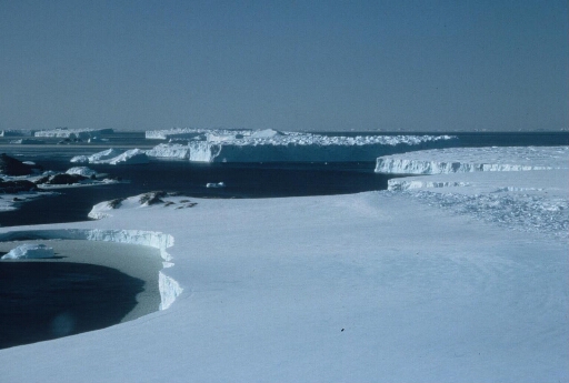 Survol vers le nord du continent en direction du nunatak du Bon Docteur, du glacier de l'Astrolabe et ses icebergs. Mer libre à perte de vue.