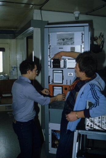 Le laboratoire de sondage ionosphérique dans le labo 1 (Bt n°25) : deux techniciens devant une baie électronique.