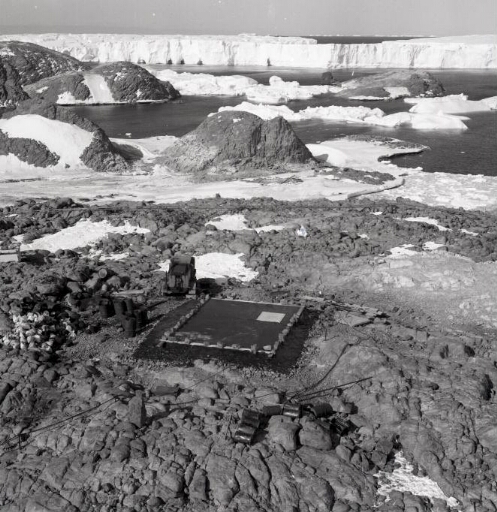 Vue aérienne plongeante sur le toit de la cave sismo juste terminé. Au loin les îles du sud, le glacier de l'Astrolabe.
