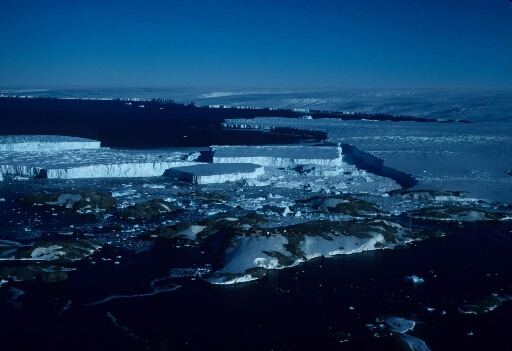 Vue aérienne vers le sud-est : l'archipel, le glacier de l'Astrolabe et le continent. Les icebergs détachés du glacier. Mer libre.