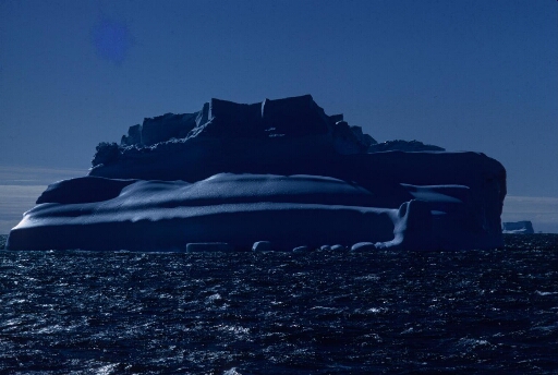 Vue depuis le Thala Dan un iceberg "remarquable": iceberg ayant basculé et présentant sa surface érodée par la mer. Mer moutonneuse.