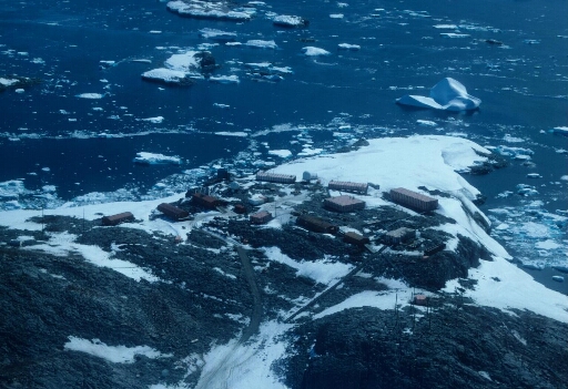 Vue aérienne du nord-ouest de l'île des Pétrels où sont concentrés les principaux bâtiments de la base. Mer libre, faible luminosité.
