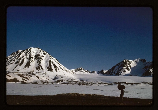 Un homme qui marche près de montagnes enneigées- mission CNRS 1965