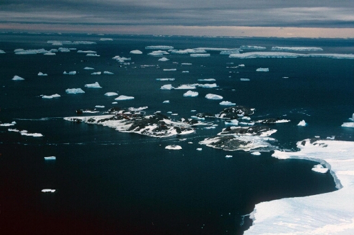 Survol, vers l'est, du continent en direction de l'archipel. A droite le nunatak. Mer libre à perte de vue, icebergs.