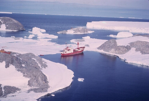 Survol du sud-est de l'île des Pétrels en direction du glacier de l'Astrolabe. Le Thala Dan amarré aux îles des Pétrels et Jean Rostand.