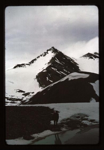 Un homme debout devant une montagne enneigée - mission CNRS 1966