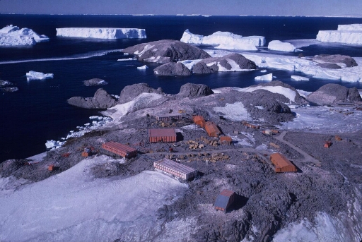 Survol du centre de la base. Au loin, les îles Buffon, Claude Bernard et Lamarck. Quelques gros icebergs dans une mer libre.