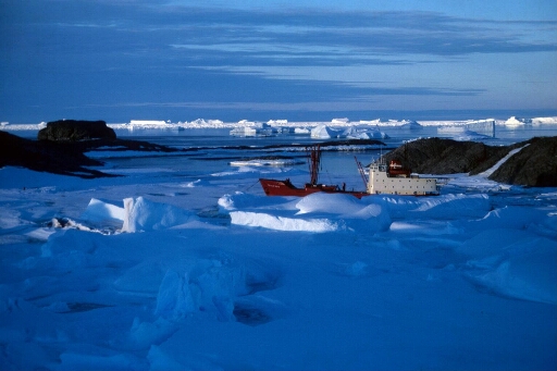 Vue en fin de journée du Thala Dan au mouillage dans l'archipel. Horizon bordé d'icebergs. Belle lumière bleue de fin de journée.
