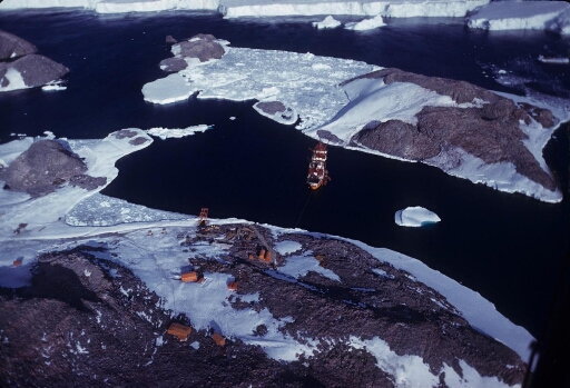 Survol du sud de l'île des Pétrels et de l'île Jean Rostand, le Thala Dan amarrré à ces deux îles. En arrière-plan le glacier de l'Astrolabe. Mer libre.