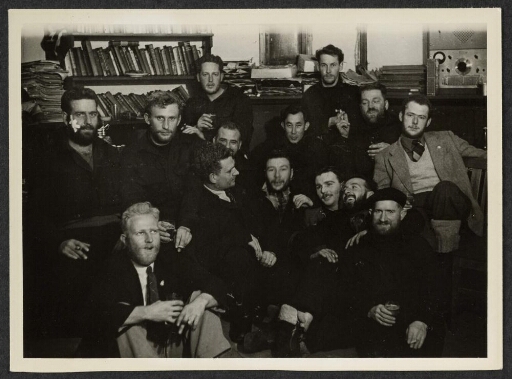 Groupe d'hommes assis et fumant.  Bibliothèque et bureau en arrière-plan