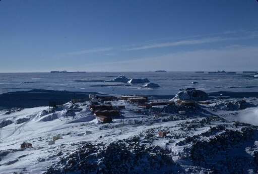 Vue prise depuis le pylône du sondeur ionosphérique vers le nord. La base enneigée, l'île du Lion, la banquise à perte de vue. Icebergs.
