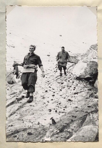 Deux hommes marchent en tenue d'alpinisme avec pour l'un, entre les mains, des bois de rennes