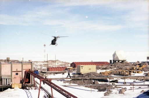 L'Alouette II survole à basse altitude le bâtiment séjour, l'anienne base, le radar météo. Au loin le pylône iono.