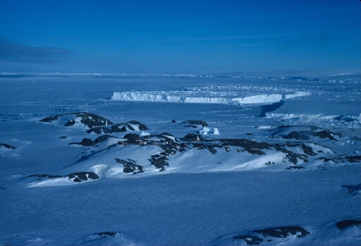 Vue aérienne vers le nord-est : l'archipel, le front du glacier de l'Astrolabe et ses icebergs, le continent. Banquise à perte de vue.