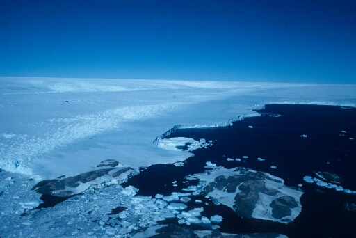 Vue aérienne en direction du sud : le nunatack du Bon Docteur, l'ile Le Maugen et le continent. Mer libre, beau temps.