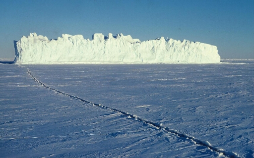 Iceberg tabulaire pris dans une banquise uniforme. Longue fissure étroite.