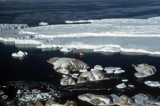 Vue aérienne en direction du sud-est : les îles Buffon, Claude Bernard et Lamarck. Le Thala Dan naviguant dans les eaux du glacier de l'Astrolabe.