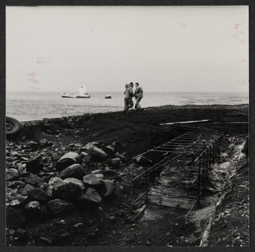 Deux hommes attachent une embarcation sur le quai