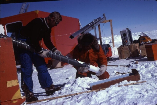 A Dôme C, le chantier de forage glaciologique : deux glaciologues procédent au démoulage délicat d'une carotte de glace.