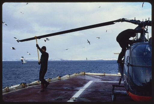 Hélicoptère posé sur le pont d'un navire (Marion Dufresne ?). Un homme prenant des mesures. Diapo 1