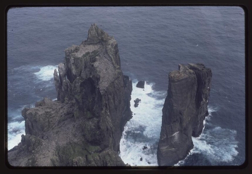 Vue aérienne sur un îlot rocheux sortant de l'océan agité