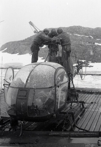 Sur le pont du Thala Dan, sous la neige, trois membres du détachement "hélico" installent le rotor de leur machine.
