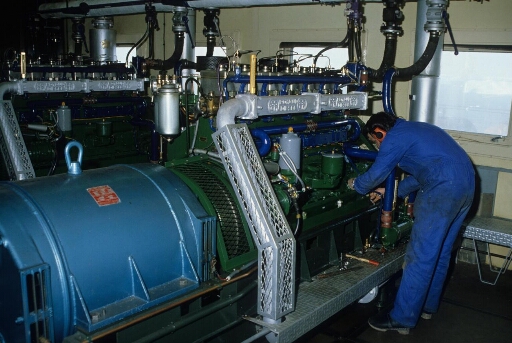 Dans la centrale électrique (Bt n°24), intervention d'un mécanicien sur le moteur poyaud de l'un des quatre groupe électrogènes.