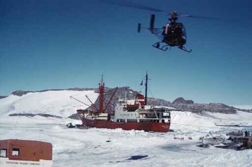 L'hélicoptère Djinn survole le Magga Dan amarré aux îles des Pétrels et Jean Rostand : déchargement du navire sur un bout de banquise.