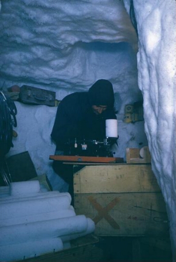 Le glaciologue Claude Lorius, dans le laboratoire creusé dans la glace, étudie une carotte de glace prélevée dans le névé.