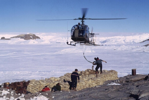 Opération de transport par hélicoptère Alouette 2 ("Sling"). Cinq opérateurs. A l'arrière-plan l'île Lamarck puis le glacier de l'Astrolabe.