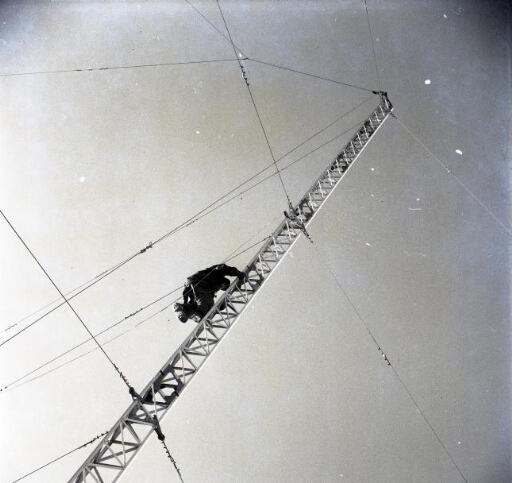 Travaux sur le pylône de la radio qu'un homme (le radio ?) escalade.
