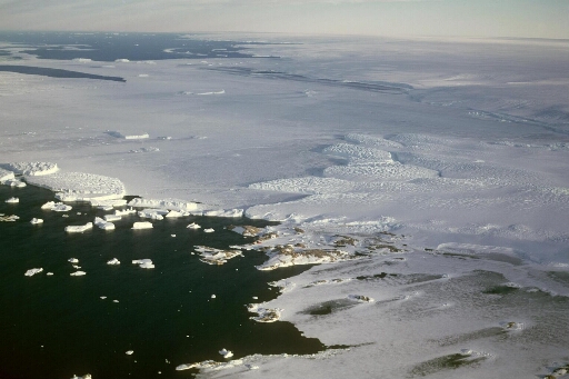Vue aérienne à très haute altitude vers le sud-est : l'archipel, le glacier de l'Astrolabe et le continent. Mer libre et banquise.