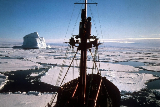Vue prise de la passerelle du Thala Dan sur le mât et la proue. Bel iceberg au milieu d'une banquise morcellée.