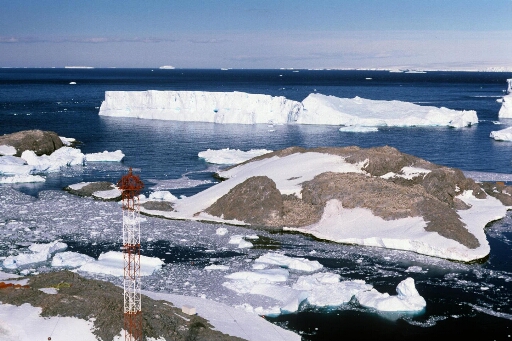 Survol, vers le sud-est, du sud de l'île des Pétrels. L'île Jean Rostand et deux beaux icebergs. Le continent à l'horizon, mer libre.