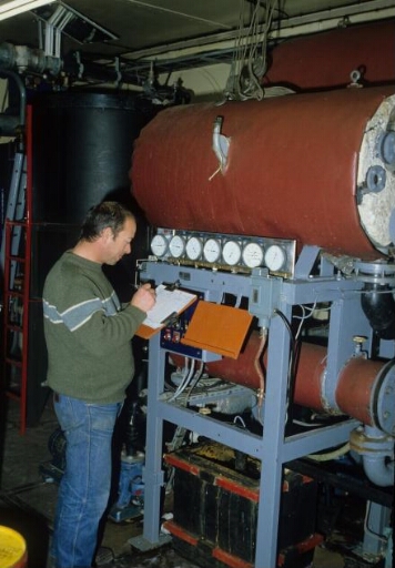 Dans la centrale électrique (Bt n°24), le distillateur d'eau de mer, sous vide et à basse température, Nerpic. Un technicien effectue des relevés.