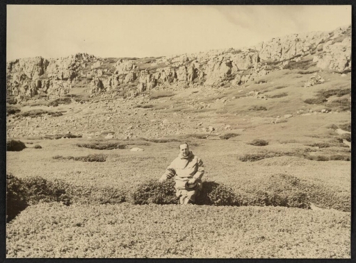 Un homme assis dans la végétation de la presquîle du Prince de Galles
