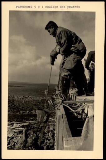 Un ouvrier tirant un seau sur le toit