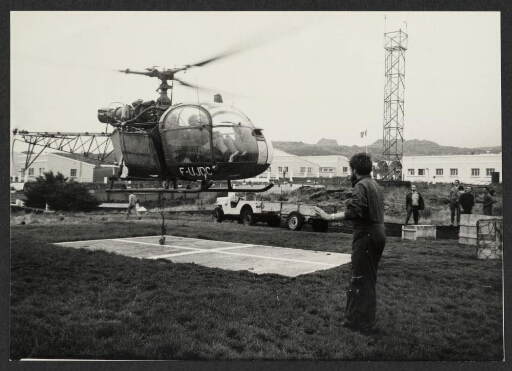 Un hélicoptère sur la zone d'atterrissage à Martin de Viviès, des personnes autour et un véhicule