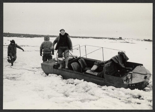 Concours 1963 : un groupe d'homme sur et autour d'une barque a moteur prise dans la glace