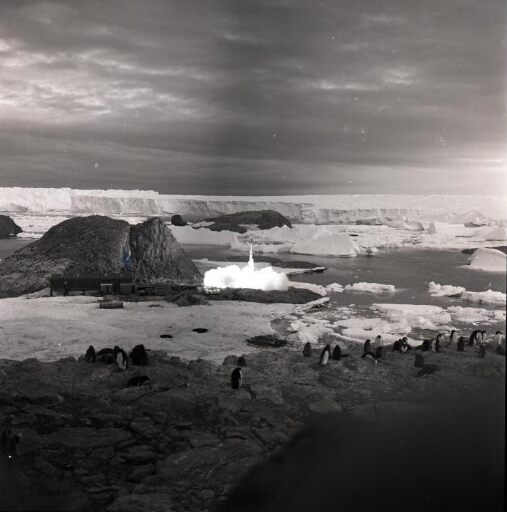 Vue éloignée d'un lancement : une fusée Dragon s'élève dans un panache de gaz de combustion. Au loin, le glacier de l'Astrolabe.